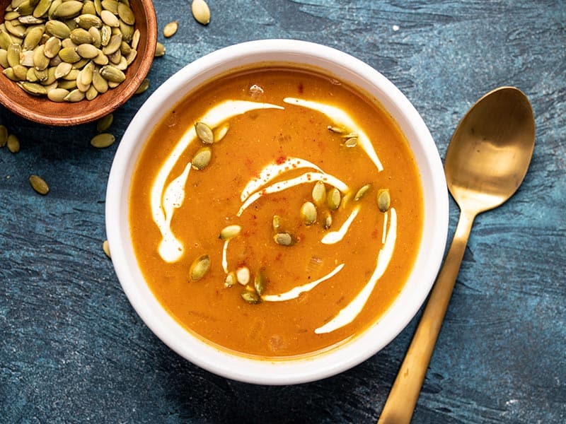 One bowl of Easy Pumpkin Soup garnished with sour cream and pepitas