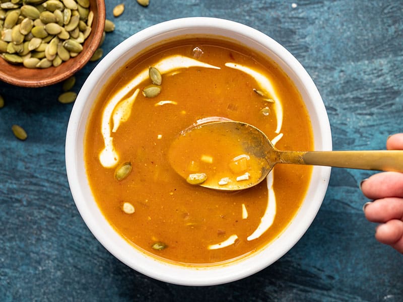 One bowl of easy tomato soup with sour cream swirled in and a gold spoon in the middle