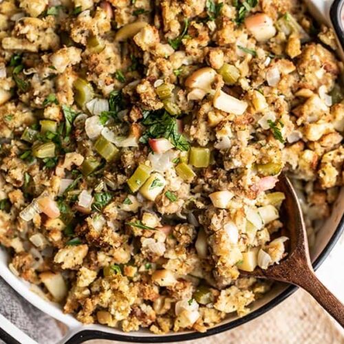 Close up overhead shot of Apple Walnut Stuffing in the casserole dish with a wooden spoon in the corner