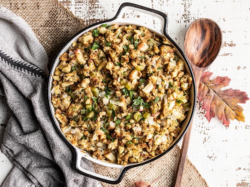 A casserole dish full of the finished Apple Walnut Stuffing, garnished with chopped parsley