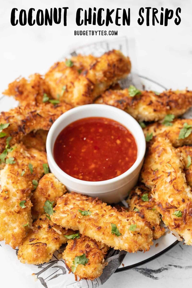 Front view of coconut chicken strips on a plate with a bowl of sweet chili sauce, title text at the top