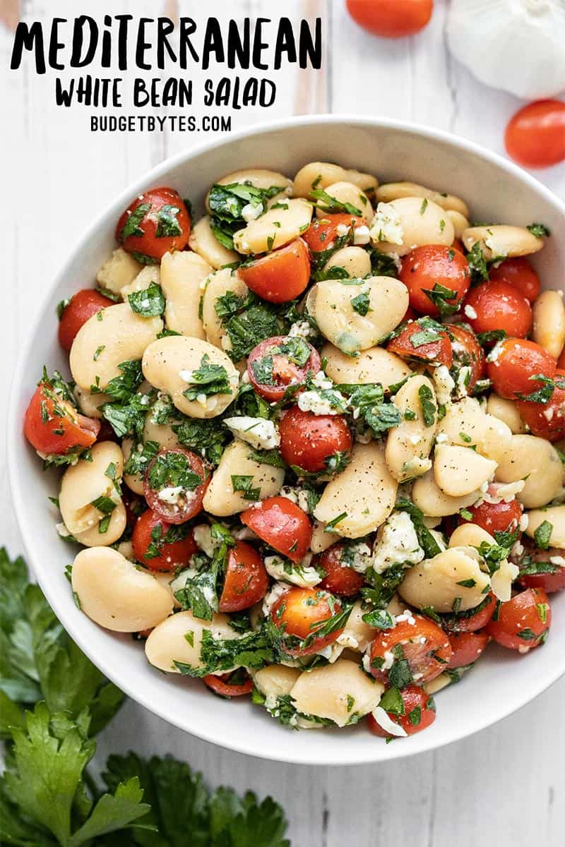 Overhead view of a bowl full of mediterranean white bean salad, title text at the top