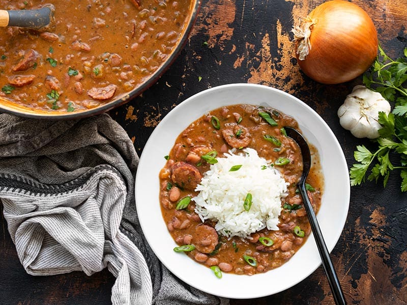 A bowl with Louisiana red beans and rice next to the pot full of cooked red beans