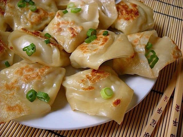 Close-up of potstickers served with chopsticks.