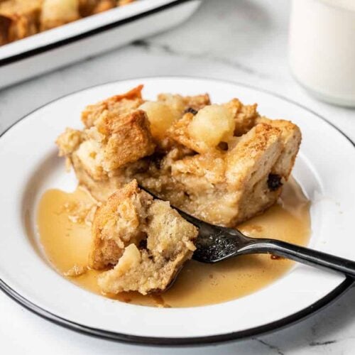 Close up of a fork cutting into a piece of apple cinnamon bread pudding