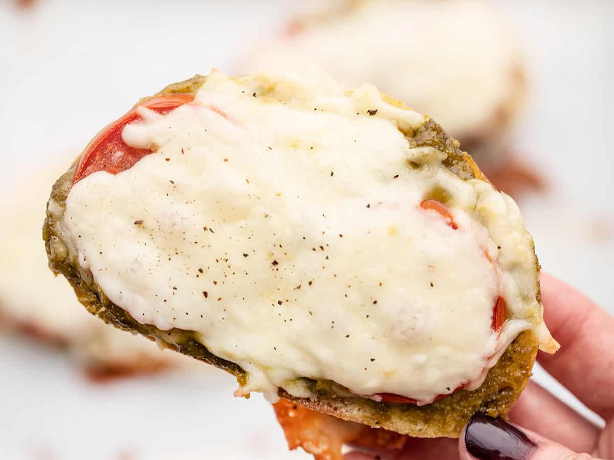 Close up of one piece of pesto cheese toast being held in a hand