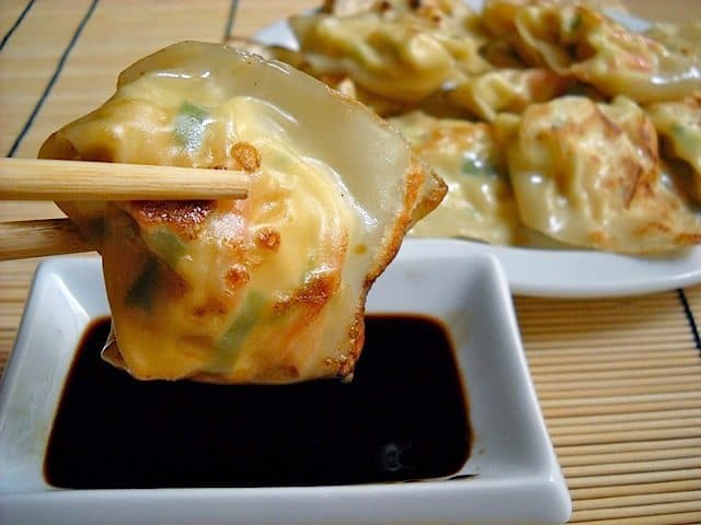 Lobster and cream cheese wontons dipped in soy sauce with chopsticks.