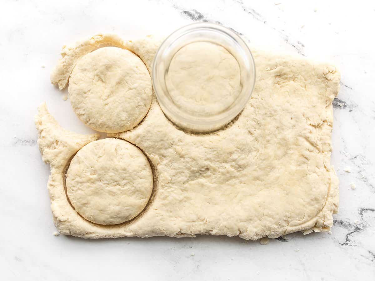 Biscuits being cut out of the dough with a drinking glass