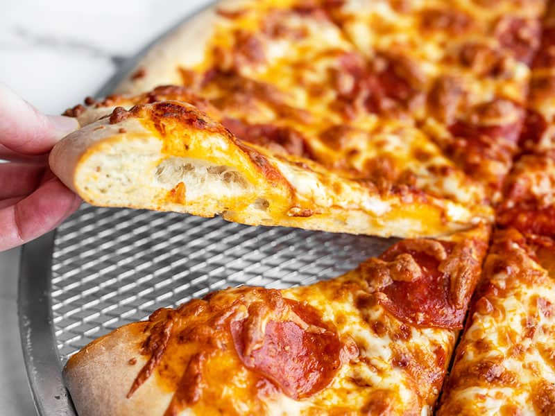 Side view of a slice of pizza being lifted from the pan