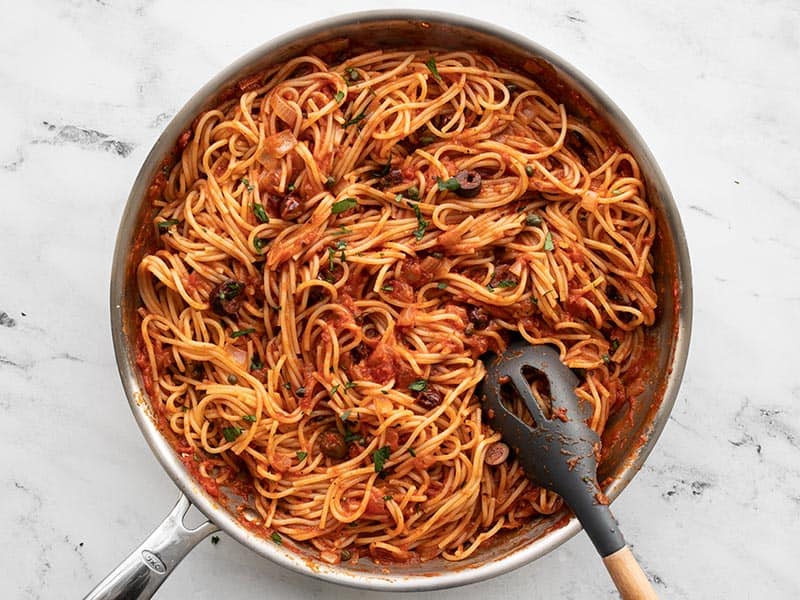 Finished pasta puttanesca in the skillet with a pasta fork