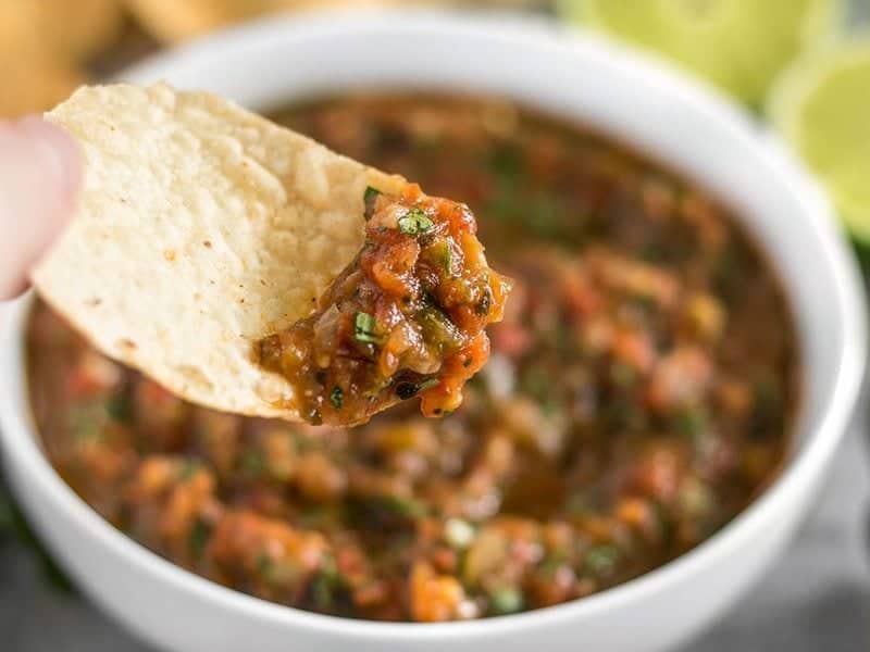 Close up of tortilla chip with fire roasted salsa on it 