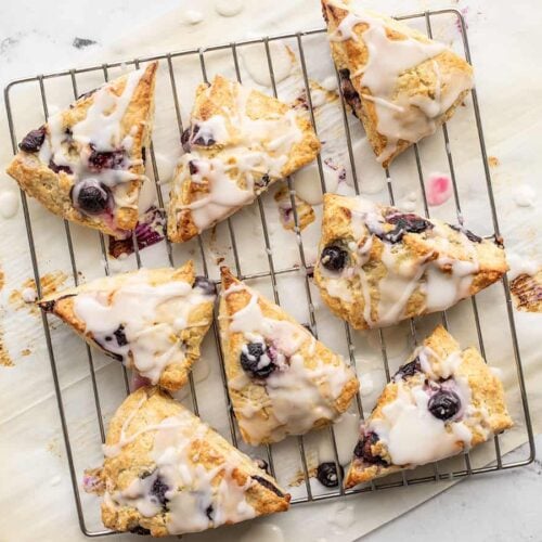 Homemade lemon blueberry scones displayed on a baking sheet.