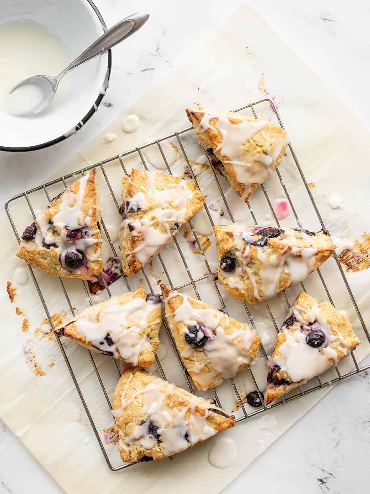 Lemon blueberry scones on a wire cooling rack drizzled with glaze