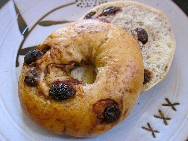 Cut cinnamon raisin bagel with cream cheese on a plate.