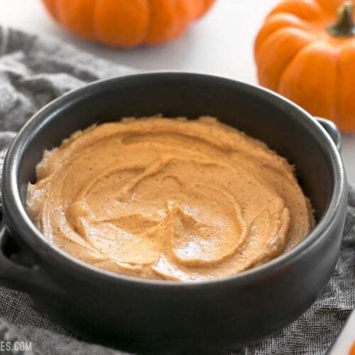 Pumpkin cream cheese spread in a bowl alongside with pumpkins.