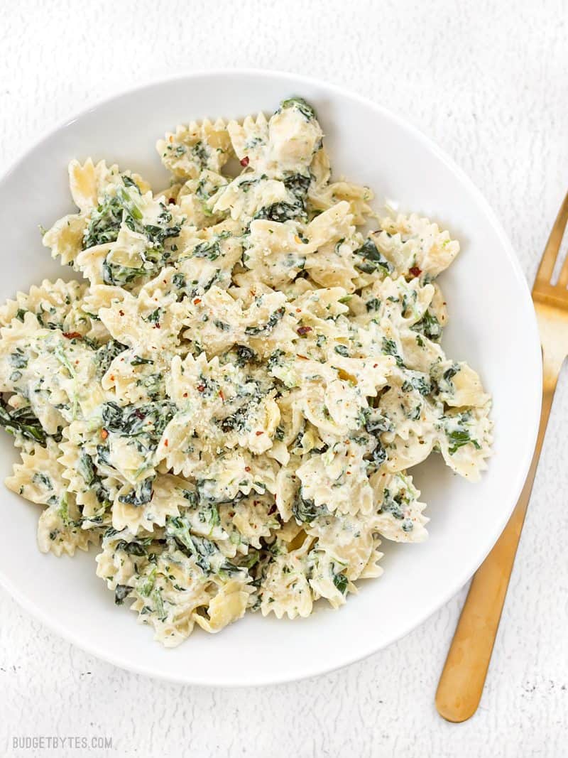 Spinach Artichoke Pasta on white plate with fork on the side 