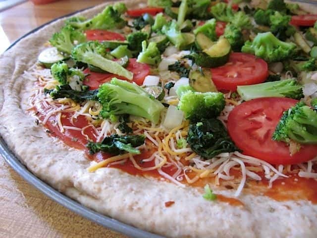 Raw pizza topped with fresh vegetables.