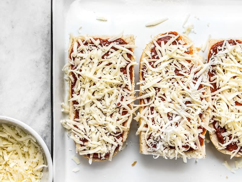 Close up of cheese being added to French Bread pieces