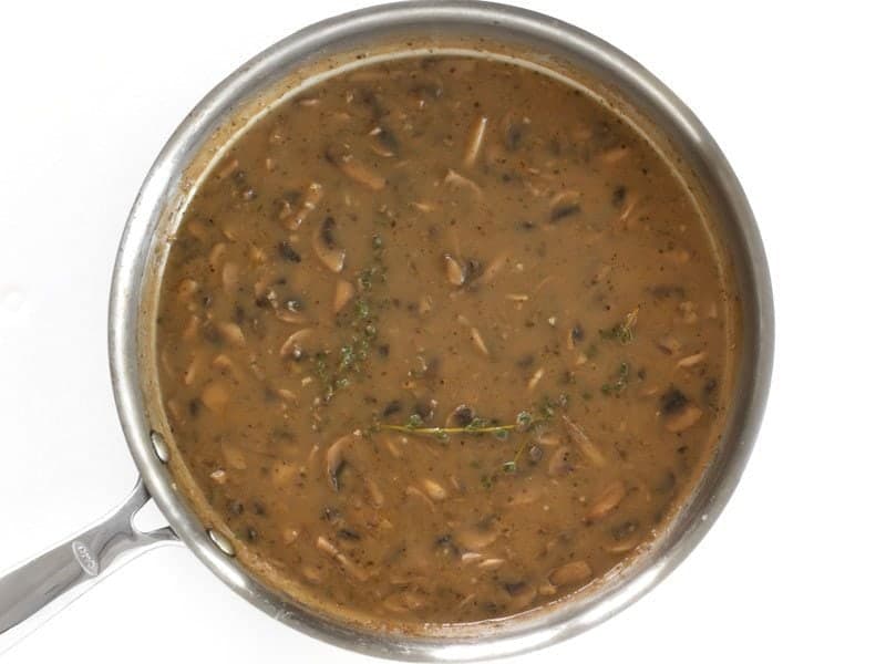 top view of herbs added to gravy in pan 