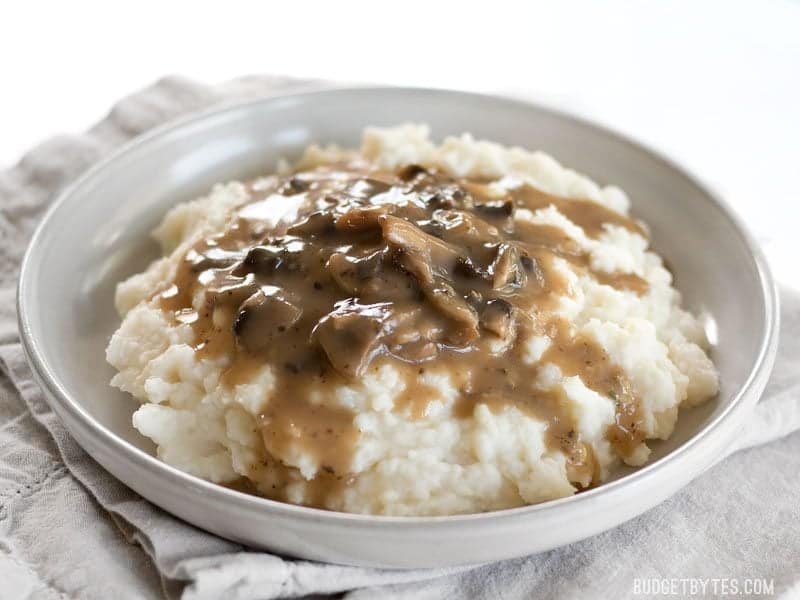 Gravy on top of plate of mashed potatoes 