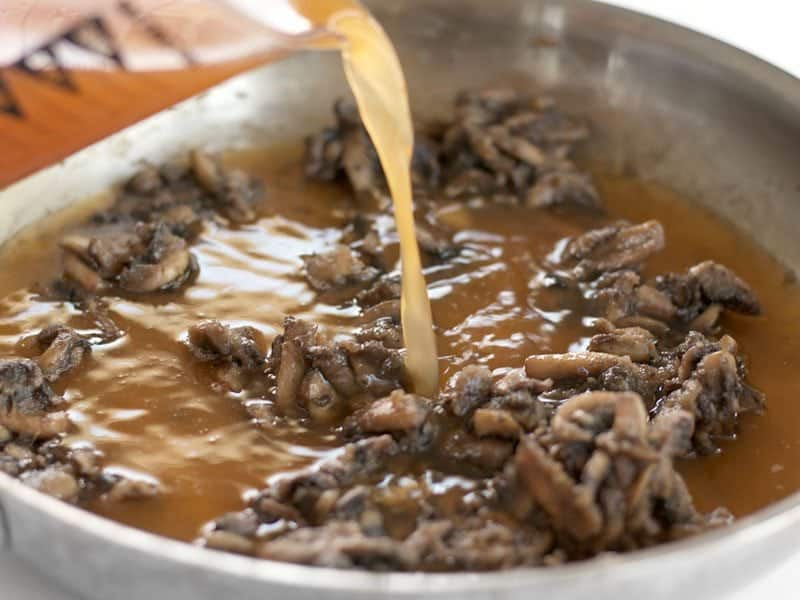 Vegetable Broth being added to mushroom mixture in pan