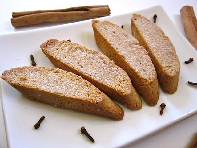 Cinnamon biscotti drizzled with glaze alongside cinnamon sticks.