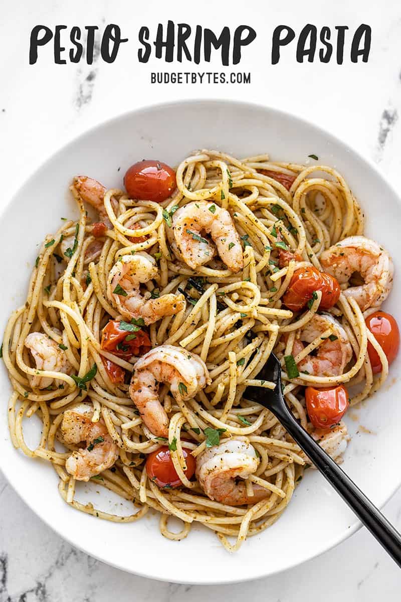 Overhead view of a bowl of pesto shrimp pasta with title text at the top