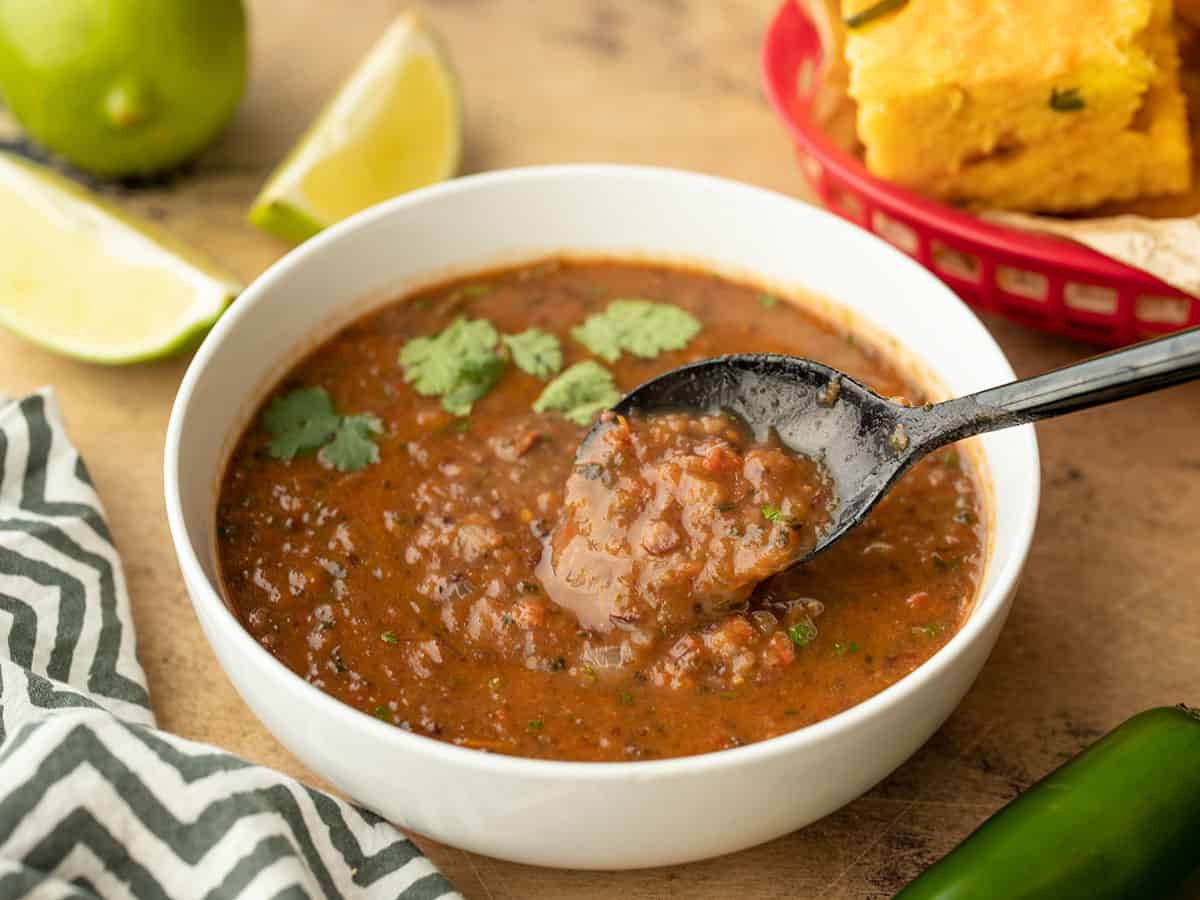 Side view of black bean and roasted salsa soup in a bowl with a spoon in the center