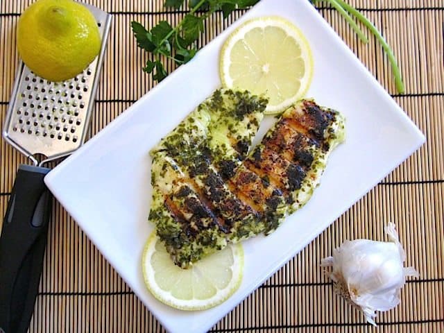 Above angle of garlic lemon fish served with lemon.