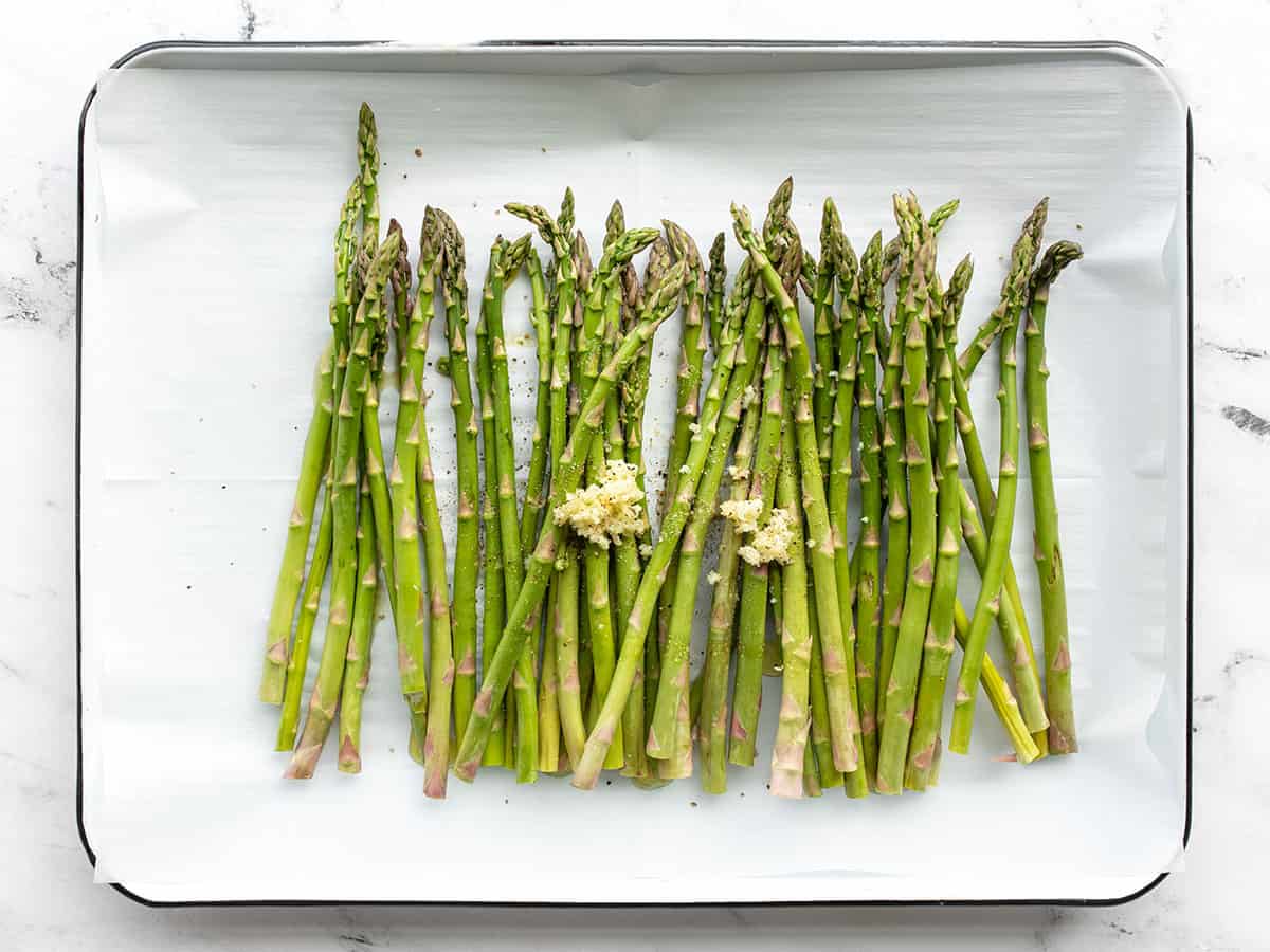 asparagus, garlic, oil, and salt on a baking sheet