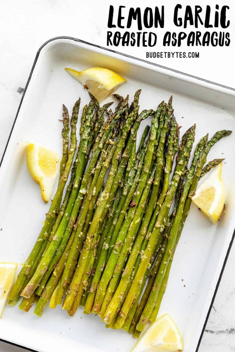 Roasted asparagus on a white sheet pan with lemon wedges, title text at the top