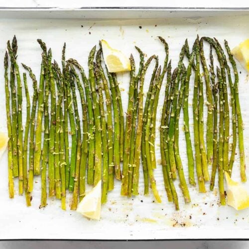 Lemon Garlic Rosted Asparagus on a sheet pan with lemon wedges