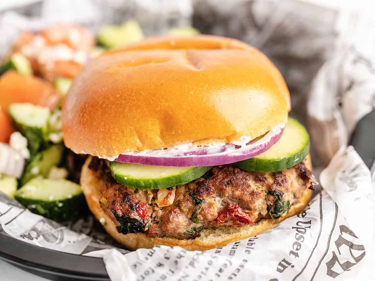 Side view of a closed Mediterranean Turkey Burger on a paper lined plate