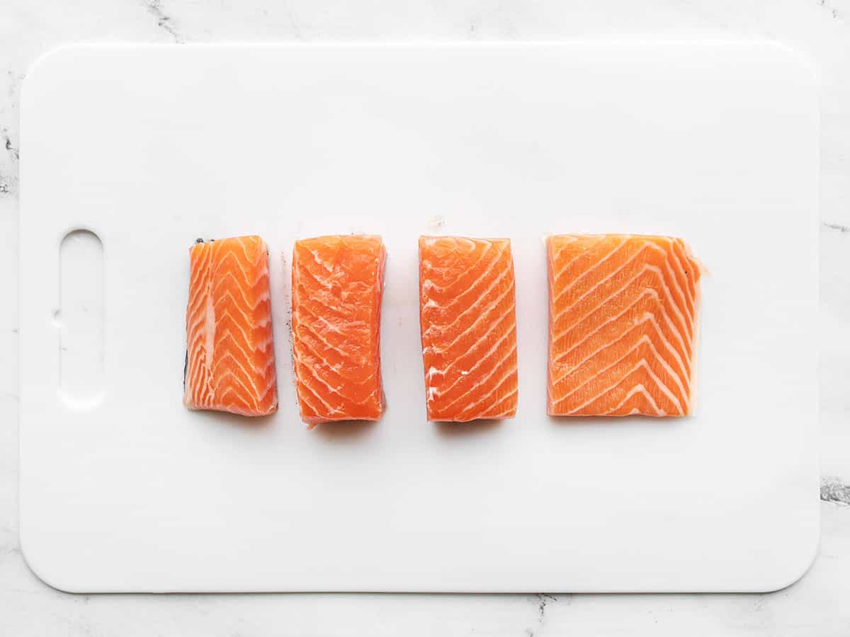 Salmon fillet cut into four portions on a cutting board