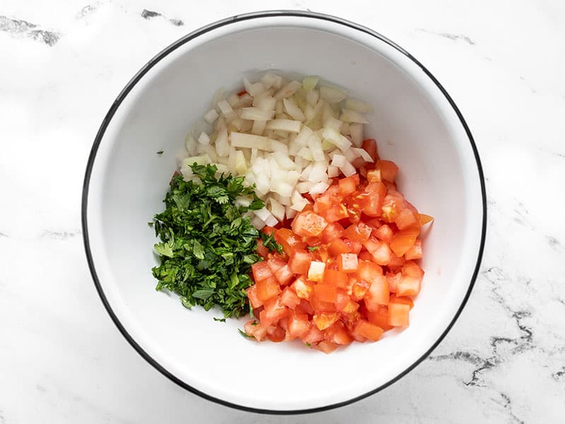 Chopped tomato onion and cilantro in a bowl.