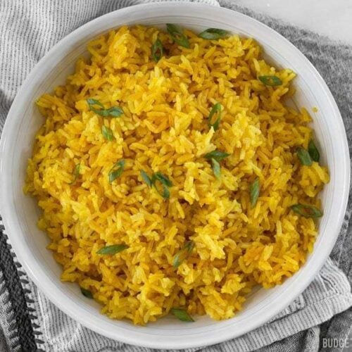 Yellow jasmine rice in a bowl on top of a table cloth.