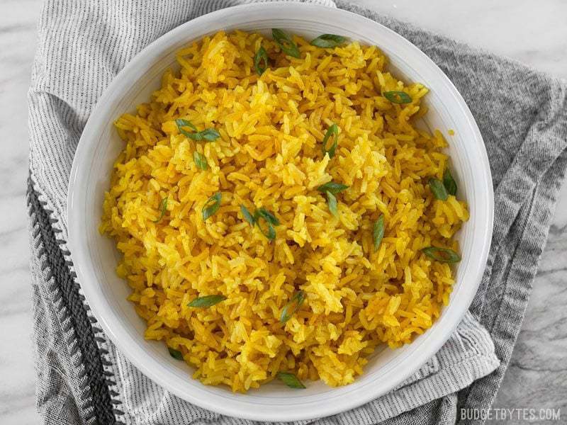 Yellow jasmine rice in a bowl on top of a table cloth.