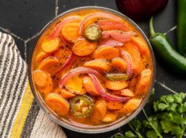 Overhead view of spicy pickled carrots in a glass bowl.