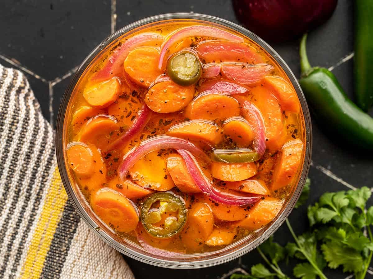 Overhead view of spicy pickled carrots in a glass bowl.