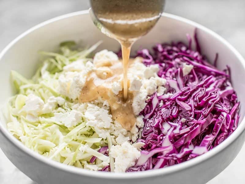 Caesar Dressing being poured on slaw 