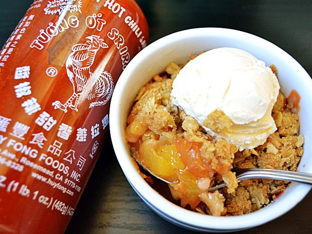 Sriracha peach crisp topped with a dollop of cream.