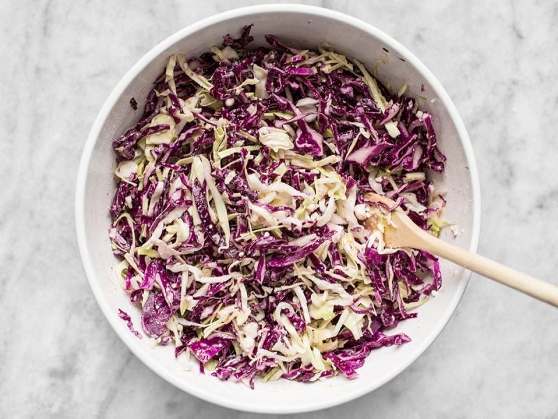 Vinaigrette Slaw with Feta finished. In bowl with wooden spoon 