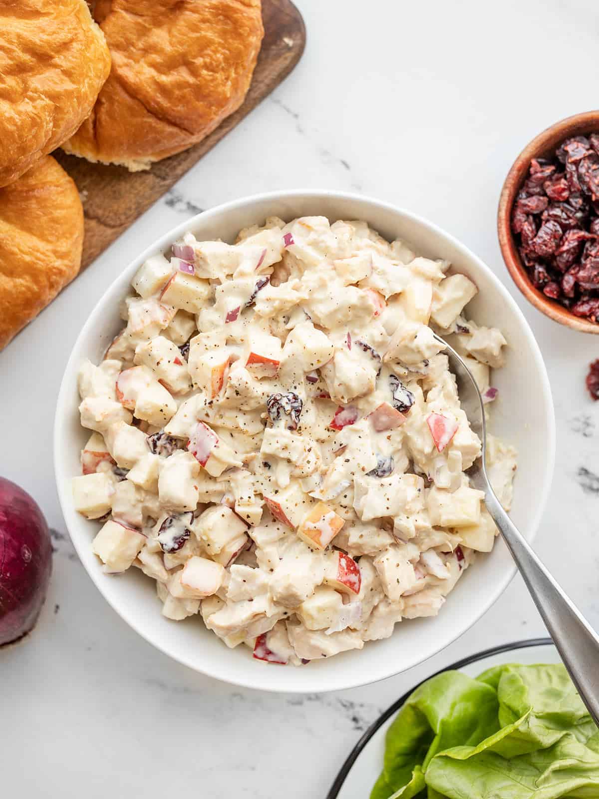 Overhead view of a bowl of chicken salad with ingredients on the sides