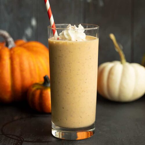 side view of pumpkin smoothie, pumpkins behind it