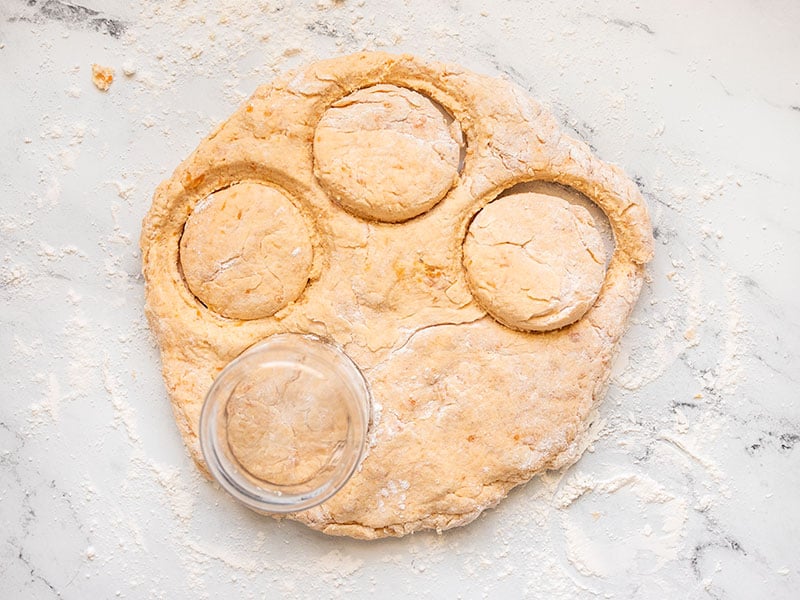 Sweet potato biscuits being cut out of the dough using a glass