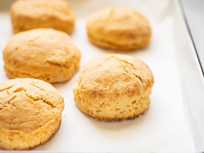 Golden brown sweet potato biscuits on the baking sheet, seen from the side.