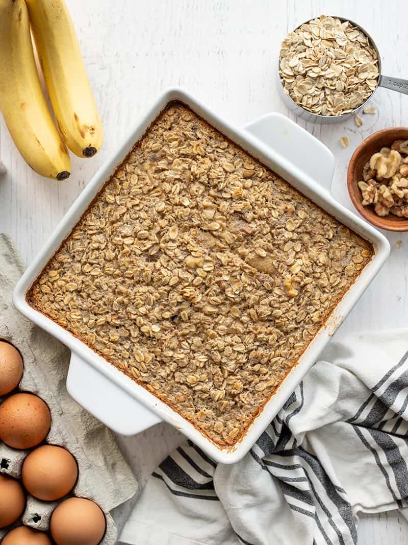 Overhead view of a casserole dish of banana bread baked oatmeal, surrounded by ingredients