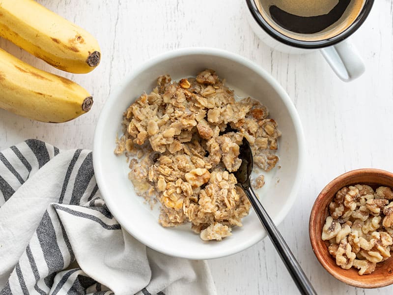 Overhead view of a bowl of banana bread baked oatmeal surrounded by ingredients