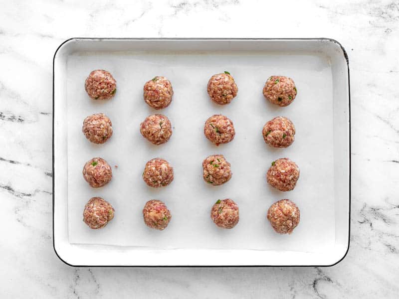 Shaped pork meatballs on a baking sheet lined with parchment paper