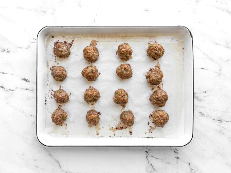 Baked pork meatballs on the baking sheet.